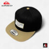 Quiksilver QS104 Manufacturing Co. Snapback Cap, showing the black crown, khaki brim, and the rectangular patch logo.