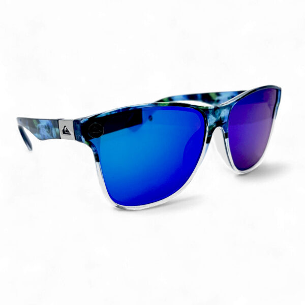 Angled side view of the Quiksilver 'Hydro-Camo' Square sunglasses, highlighting the clear frame, the subtle hydro-camo pattern on the temple arm, and the ombre blue mirror lens.