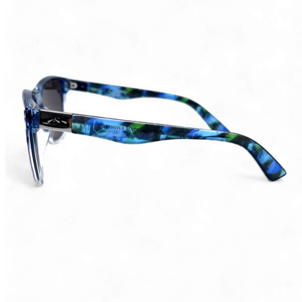 Side view of the Quiksilver 'Hydro-Camo' Square sunglasses, featuring the clear frame, subtle camo pattern on the temple arm, and the profile of the ombre blue mirror lens.