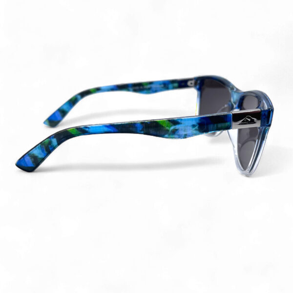 Right side view of the Quiksilver 'Hydro-Camo' Square sunglasses, showcasing the clear translucent frame, the subtle camo pattern on the temple arm, and the ombre blue mirror lens profile.