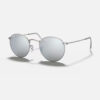 Left angled view of the Ray-Ban Round Metal RB3447 sunglasses, showing the thin matte silver metal frame and the bright silver flash circular lenses.